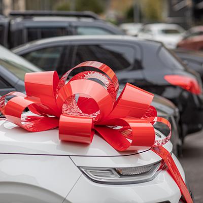 A white car with a red ribbon gift.